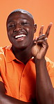 Peace sign, happy and face of black man in studio for social media, confidence and trendy style. Fashion, smile and portrait of person in cool clothes, outfit and emoji on orange background in Kenya