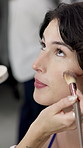 Hands, makeup brush and woman in dressing room with foundation, application and face for fashion show. People, runway model and artist with tools, equipment and powder with cosmetics for beauty