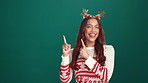 Christmas, face and woman in studio, pointing and announcement on green background. Portrait, happy person and model with holiday season, hand gesture and Xmas hat with smile and product giveaway
