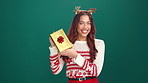 Excited, christmas gift and face of woman in studio for celebration, giveaway or surprise. Happy, xmas holiday and portrait of female person with present box for festive tradition by green background