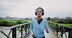 Running, fitness and woman in city, training and headphones for podcast, energy or wellness. Outdoor, happy person or runner with practice, cardio or streaming audio with workout, health or challenge