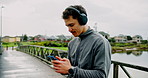 Outdoor, exercise and man with smartphone, headphones and listening to radio. Person, runner and athlete in city, cellphone and headset with fitness, track progress and podcast with app and workout