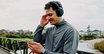 Outdoor, fitness and man with smartphone, headphones and listening to music. Happy person, runner and athlete in city, cellphone and headset with exercise, radio and app for song, wellness and smile