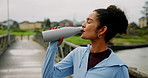 Runner, fitness and girl drinking water on bridge for running break, hydration or cardio challenge. Burnout, athlete and liquid bottle outdoor for training refresh, exercise recovery and workout rest
