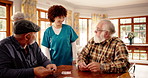 Nurse, elderly men and playing cards with talk, smile and contest with cognitive challenge in retirement. Senior friends, people and caregiver with game, competition and happy with bridge in hall