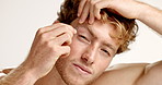 Tweezer, eyebrows and face of man in studio for grooming, hygiene or self care with beauty tool. Facial epilation, portrait and male person with plucking for hair removal routine by white background.