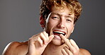 Studio, man and face with floss for teeth whitening, hygiene and grooming with check for dental care. Space, male person and portrait with oral string for wellness, tooth health and gray background