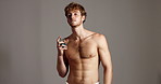 Studio, man and face with cologne for skincare, dermatology and confidence with hygiene in towel. Mockup, male person and cosmetics in portrait for perfume, body odor and fragrance in gray background
