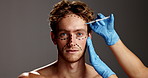 Man, face and syringe for plastic surgery in studio with lines, aesthetic or dermatology by background. Person, cosmetic surgeon and needle for skin, portrait and filler with mock up space in Spain