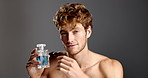 Face, cologne and man in studio, cosmetics and dermatology treatment on gray background. Portrait, happy person and model with spray, confidence and beauty product with fragrance bottle and grooming
