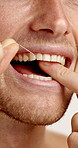 Dental health, floss and mouth of man in studio for plaque removal, hygiene or grooming in morning. Oral care, wellness and person with string for cleaning teeth, fresh breath or cavity prevention.