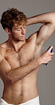 Morning, grooming and man with spray, armpit and fresh scent with deodorant, fragrance or cosmetics. Studio, shirtless and person with product for underarm, gray background and self care for odor