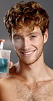 Cologne, face and smile of shirtless man in studio for fresh aroma, grooming or hygiene product. Body, fragrance and smell with happy model on gray background for advertising or marketing of scent