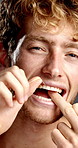 Man, mouth and floss in studio for dental care, hygiene and grooming for teeth whitening with smile. Cleaning, male person and portrait with string for wellness, tooth health and oral treatment