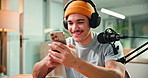 Man, phone and happy with mic for podcast with typing, scroll or reading chat for live stream. Person, influencer and smile with smartphone, app or social network for content creation at media agency
