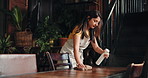 Woman, waitress or cleaning table with spray bottle for hospitality, hygiene or accommodation in cafe. Female person, cleaner or wiping surface with cloth for bacteria or dirt removal in coffee shop
