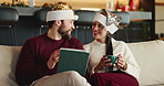 Christmas, coffee and tablet with couple on sofa in living room of home for online shopping. App, ecommerce and festive with people in apartment to search internet for holiday or vacation gifts