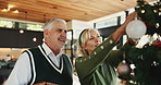 Senior, happy couple and christmas with tree decor for celebration or christian holiday at home. Elderly, man and woman hanging with smile, bauble or ornaments for december or festive decorations