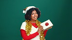 Christmas, face and woman with gift, excited and facial expression on green studio background. Portrait, person or model with tradition, holiday season or festive with Xmas present, surprise or smile