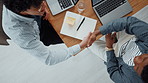 Above, handshake and business people in office, notebook and agreement for creative project. Web designers, shaking hands or employees in workplace, laptop and partnership for tasks, deal or deadline