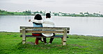 Couple, relax and park bench with lake view, love and hug with bonding for date on holiday. People, man and woman for embrace, sightseeing or vacation with care outdoor and back by water in nature