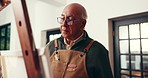 Creative, senior man and painting in home for inspiration, artwork and talent with easel. Elderly person, happy painter and art on canvas for retirement hobby, craft and artist drawing with tools