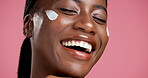 Black woman, face cream and beauty in studio for skincare, facial hydration and shine. Happy, female person and spf lotion with moisturising benefits, treatment glow and self care on pink background