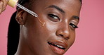Face, skincare and black woman apply serum for beauty, hyaluronic acid or vitamin c. Portrait, happy model or dropper for cosmetic, collagen or essential oil for dermatology on pink studio background