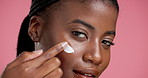 Face, black woman and cream for skincare in studio for beauty, facial hydration and shine. Smile, female person and spf lotion of moisturiser benefits, treatment glow and self care on pink background