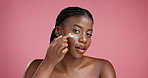 Face, black woman and apply moisturizer for skincare, lotion or collagen treatment for dermatology. Portrait, happy model and cream for cosmetics, beauty detox or hydration on pink studio background