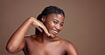 Beauty, skincare and hands with face of black woman in studio for smile, glow and dermatology. Shine, hydration and grooming with person on brown background for self care, cleaning and detox