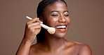 Apply, brush or face of happy African model in studio for glow, makeup or skincare portrait. Smile, playful or happy black woman on brown background with beauty cosmetics, confidence or facial tools