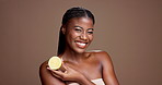 Happy, face and black woman with lemon for vitamin c, brightening benefits or beauty in studio. Brown background, healthy shine and female person with fruit for detox, cosmetics and diet for skincare