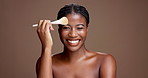 Laughing, apply or face of black woman with brush for glow, makeup or skincare portrait. Happy, funny or African female model on brown background with beauty cosmetics, confidence or facial tools