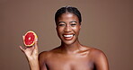 Laugh, face or happy black woman with grapefruit for brightening, beauty or space. Brown background, smile or African model in studio with tropical citrus for healthy glow, vitamin c and skincare