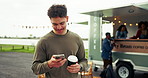 Coffee, outdoor and man with phone for networking, social media or communication by food truck. Smile, cappuccino and male person waiting for date with cellphone for texting or contact at mobile cafe