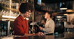 Bartender, man and tablet at pub for stock take, inspection and inventory checklist at small business. Trainee, bar manager and digital tech with app for menu, pos system and hospitality review