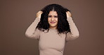 Hair care, confused and face of woman in studio with beauty, messy or damage for treatment. Upset, portrait and female person from Mexico with frizz for curly hairstyle fail by brown background.