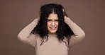 Hair care, upset and face of woman in studio with beauty, messy or damage for treatment. Confused, portrait and female person from Mexico with frizz for curly hairstyle fail by brown background.