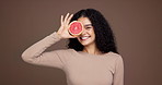 Happy woman, face and studio with grapefruit for diet or nutrition on a brown background. Portrait, female person or model with smile or natural organic fruit for vitamin c, health or fiber on space