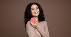 Happy woman, face and diet with grapefruit in studio for health or detox on a brown background. Portrait, female person or model with smile or natural organic fruit for fiber or vitamin C on space