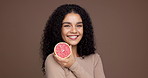 Happy woman, face and vitamin C with grapefruit in studio for health or detox on a brown background. Portrait, female person or model with smile or natural organic fruit for fiber or diet on space
