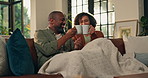 Mature African couple, coffee and toast on sofa with smile, blanket and relax with bonding in home. Man, woman and happy with drinks, celebration and love with thanks on anniversary in living room