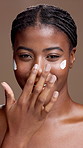 Face, skincare and black woman apply cream for beauty, sunscreen and laugh. Portrait, cosmetics and smile with lotion for dermatology, moisturizer and collagen for health on brown studio background