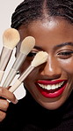 Makeup, brush and face of black woman with lipstick in studio for cosmetics, beauty and makeover. Cosmetology, aesthetic and portrait of person with tools for salon products on studio background