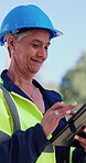 Woman, engineer and typing with tablet at construction site with smile, notes and safety report. Mature person, architect and tech with app, inspection and property development project in Mexico