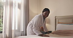 Smile, black woman and making bed in hotel room for morning routine, maintenance and getting ready. Tourist, hospitality and cleaning in bedroom of resort for travel, vacation and holiday with robe