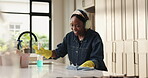 Headphones, woman and cleaning kitchen with spray for surface disinfection, dancing or housekeeping. Maid, music playlist and black person with gloves in home for daily chores, singing and sanitation