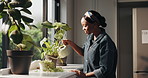 Home, watering plants and black woman with smile, gardening and eco friendly with hydration. African person, apartment and gardener with happiness, natural growth and leisure with hobby and spring