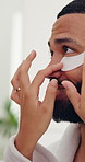 Happy couple, eye patch and help with product for vitamin C, collagen or anti aging in bathroom. Man, smile and woman with cosmetics or facial mask for beauty, skincare or face treatment in house